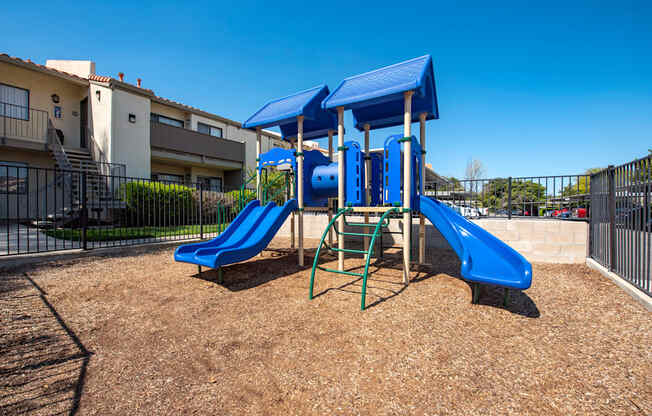A playground with a blue slide and a blue canopy.