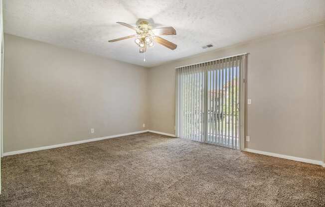 Omaha, NE Maple Ridge Apartments. A bedroom with a ceiling fan and a sliding glass door