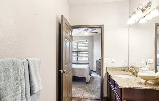 a bathroom with a mirror and a sink and a door to a bedroom