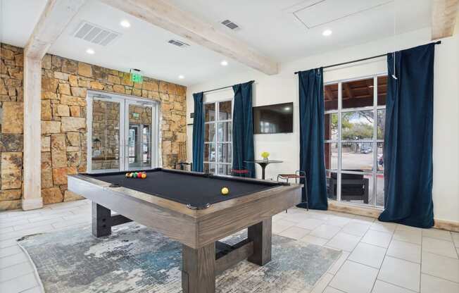 a pool table in a house with a stone wall and glass doors