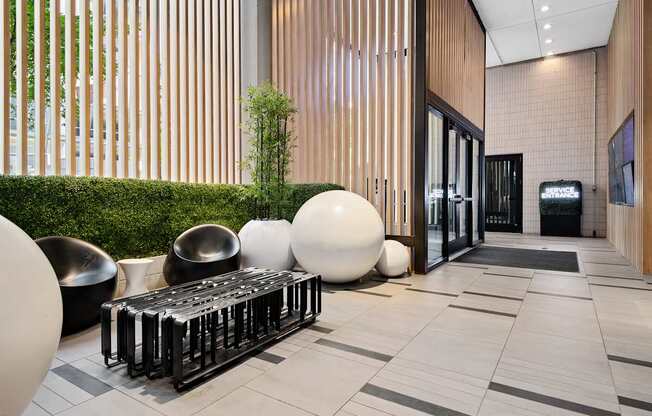 A modern lobby with a green hedge and a black and white bench.