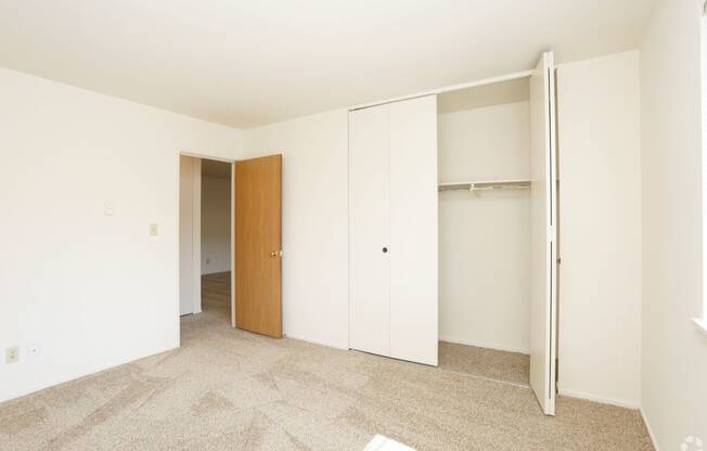 a bedroom with white walls and a closet with a door