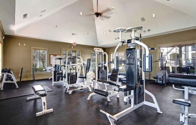 a gym with a lot of exercise equipment and a ceiling fan
