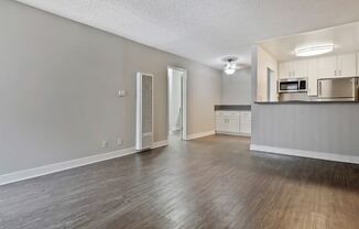 an empty living room and kitchen with wood flooring