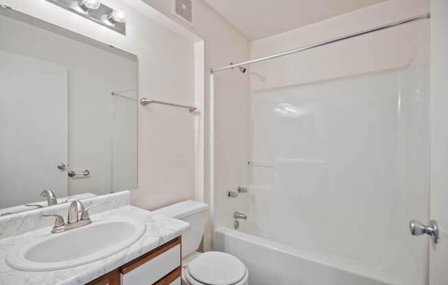 A white bathroom with a toilet, sink, and bathtub.