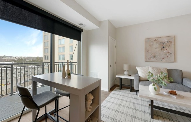 a living room with a table and a couch and a balcony