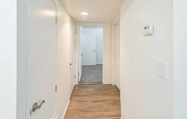 a long hallway with white walls and a wood floor