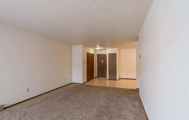 an empty living room with carpet and white walls. Moorhead, MN South Park Apartments