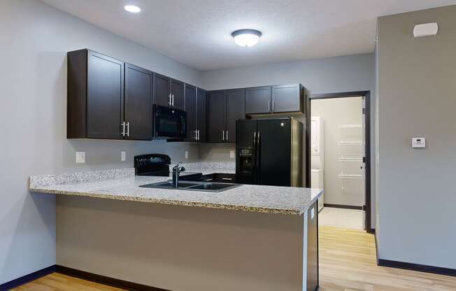 a kitchen with dark cabinets and a granite counter top