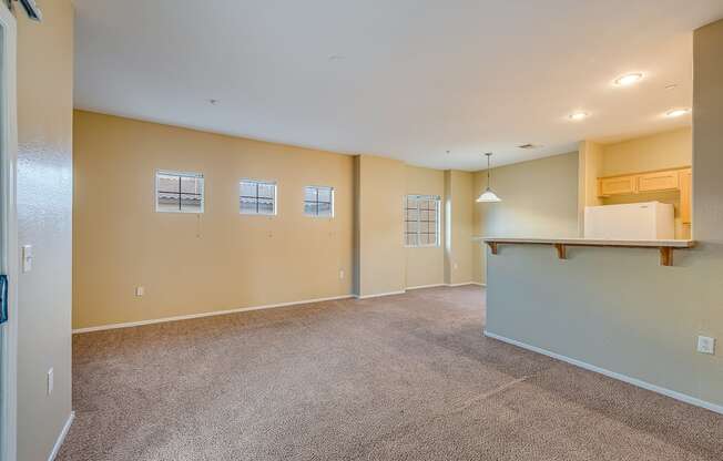 the living room and kitchen of an empty home with carpeted floors and a counter