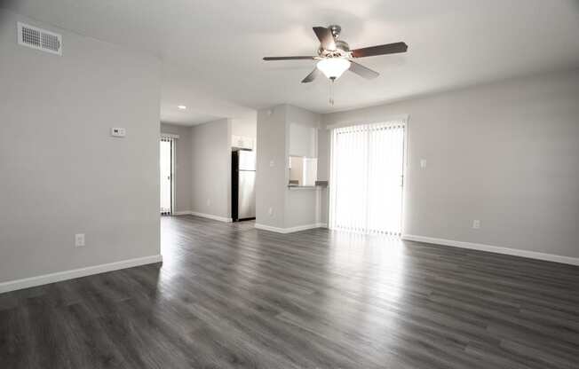 an empty living room with wood floors and a ceiling fan