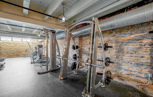 A gym with a brick wall and a row of exercise machines.