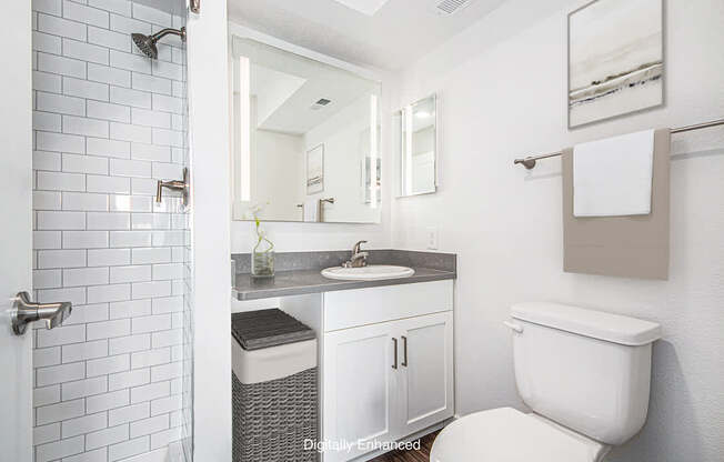 A white toilet is in a bathroom with a white tiled shower.