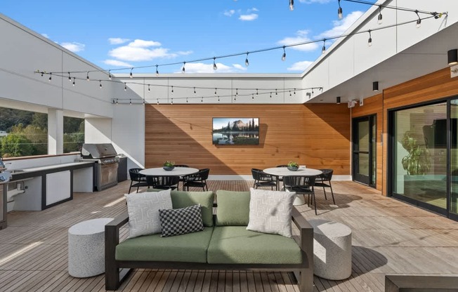 A modern outdoor deck with a green couch and a table.