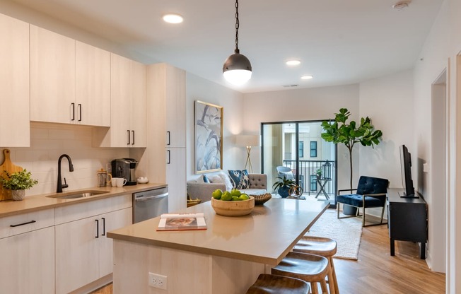 a kitchen with white cabinets and a large island with a bowl of fruit on it  at Century West Pryor, Lee's Summit, MO