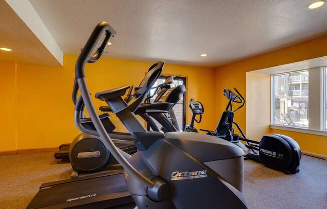 The fitness center at Olde English Village, offering exercise machines and free weights for residents.