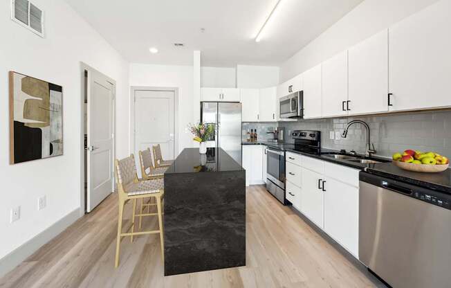 A modern kitchen with a black granite island and stainless steel appliances.