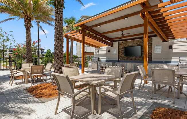 A patio with a table and chairs under a wooden pergola.