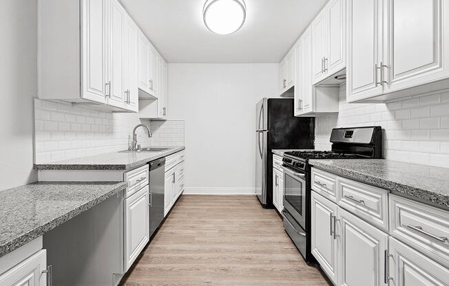 Large white tiled kitchen with stainless steel oven, microwave, and fridge.