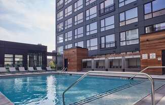 A swimming pool is surrounded by a wooden deck and lounge chairs.