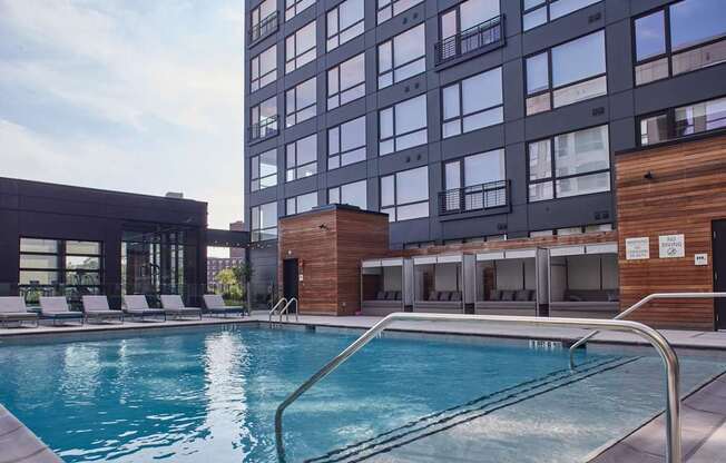 A swimming pool is surrounded by a wooden deck and lounge chairs.