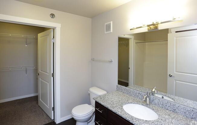 A bathroom with a toilet, sink, and mirror.