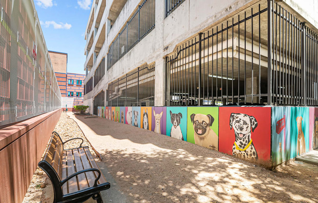a bench in front of a wall with paintings of dogs on it