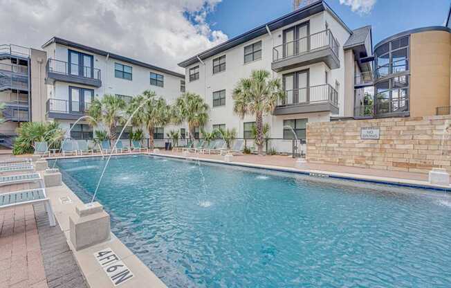 Resort style pool with palm trees and lounge chairs at Vue Live Oak Apartments, Texas, 75204