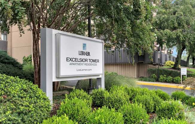 A sign for the Lerner Excelsior Tower Apartment Residences stands in front of a building.