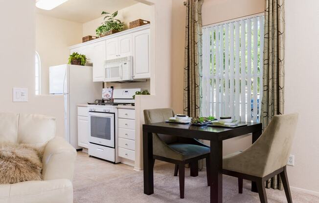 A kitchen with a table and chairs in front of a window.