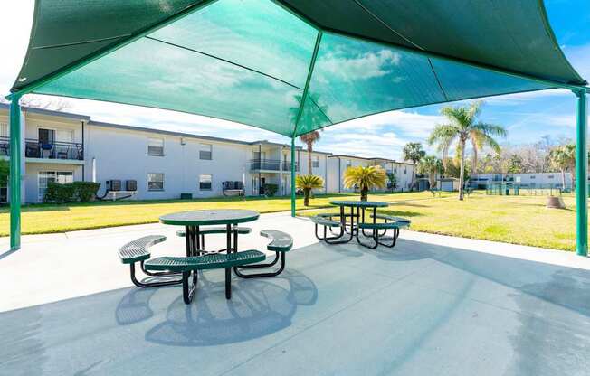 A green canopy over a picnic table in a sunny outdoor setting.