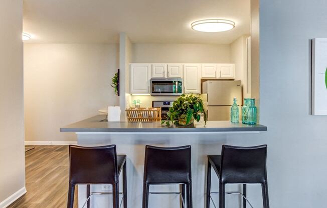 a kitchen with a counter and three chairs