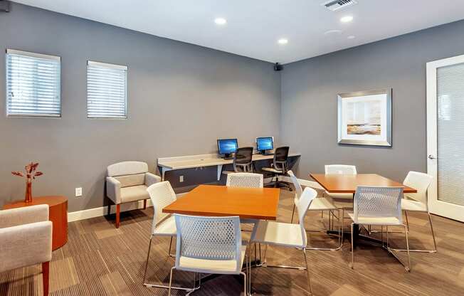 a room with several tables and chairs with computers on top of them