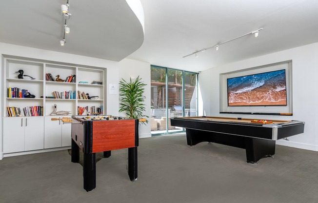 A room with a pool table and a bookshelf.