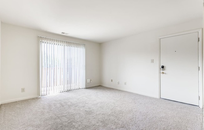 A room with a carpeted floor and a sliding glass door