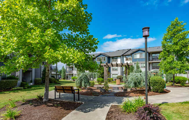 a park with trees and a bench in front of an apartment building