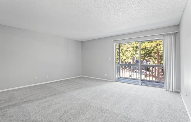 an empty bedroom with a sliding glass door and a balcony