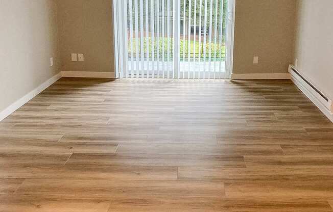 A room with wooden flooring and a sliding glass door.