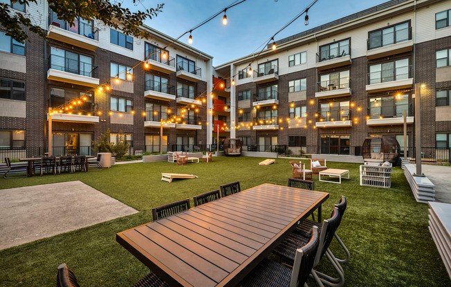 A wooden table is surrounded by chairs in a courtyard.