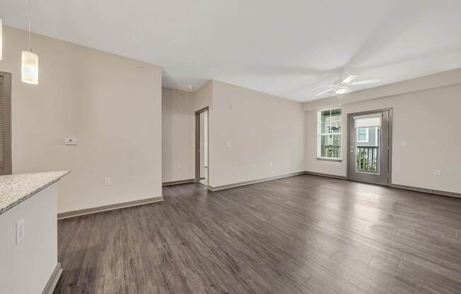 the living room of an empty home with wood flooring and a door to a