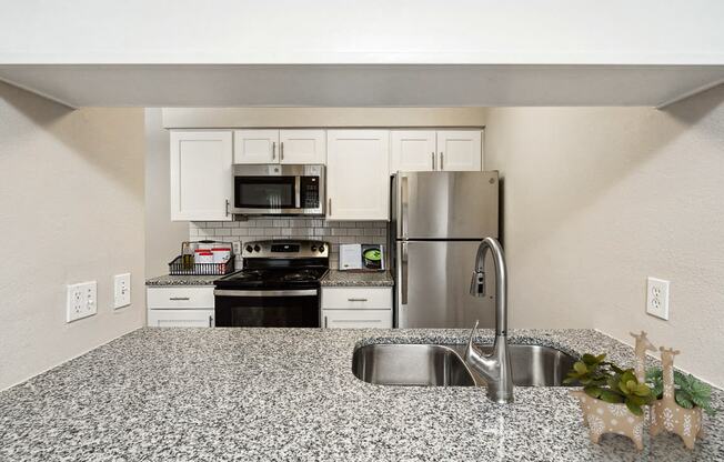 a kitchen with granite counter tops and stainless steel appliances at The Reserve At Barry Apartments, Kansas City