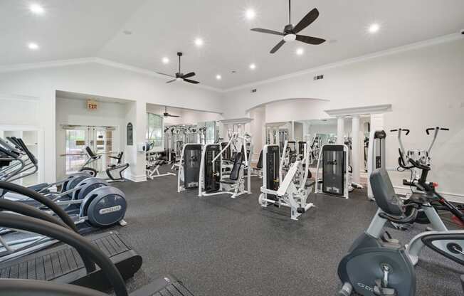 a gym with weights and cardio machines and ceiling fans