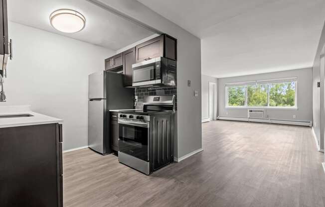 the living room of an apartment with a kitchen and a large window