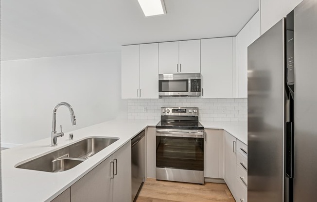 A modern kitchen with stainless steel appliances and white cabinetry.