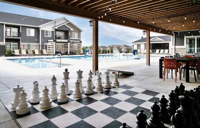 a large chess board in front of a swimming pool