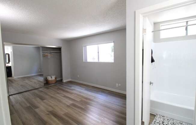 an empty living room and a bathroom with a shower and a bath tub