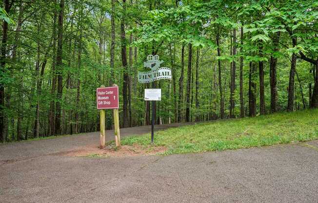 A sign for the Film Trail , Museum, Visitor Center, and gift shop is in front of a wooded area.
