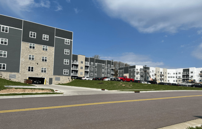 a view from the street of an apartment complex with a blue sky in the background