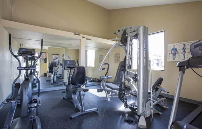 a gym with cardio equipment and weights on the floor