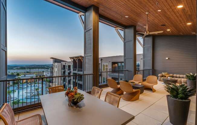 A balcony with a table and chairs overlooking a body of water.